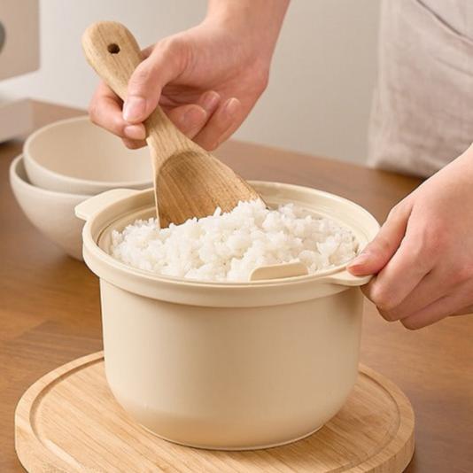 a person scooping rice into a bowl with a wooden spoon